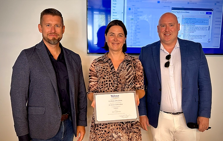 Julianna Sandholm-Bark holding her promotion certificate alongside Dr. Ryan Guffey and Eric Click.
